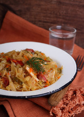 sauerkraut with sausage onions and carrots in a white plate