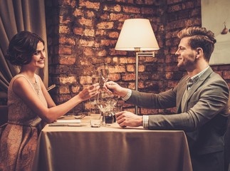 Stylish wealthy couple toasting with champagne in a restaurant.