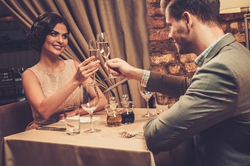 Stylish wealthy couple toasting with champagne in a restaurant.