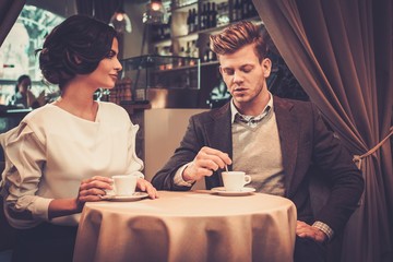 Stylish wealthy couple drinking coffee in restaurant.