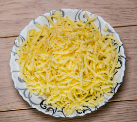 bowl of grated cheese on wooden table background