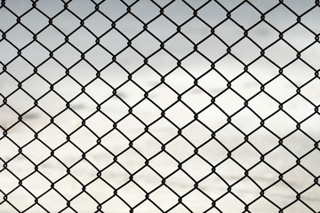 Wire mesh fence on a background of gray concrete.