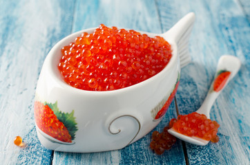 Red salmon caviar on a blue wooden background