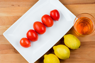 Naklejka na ściany i meble pomodori e limoni su piatto bianco e tagliere, bicchiere con aperitivo