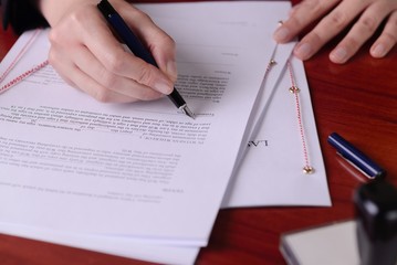 Closeup of a hand signing a last will by a pen.