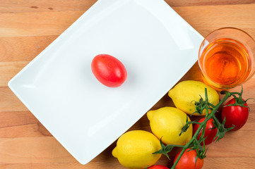 Preparazione dell'aperitivo, con pomodori e limoni. Un piatto bianco su tagliere