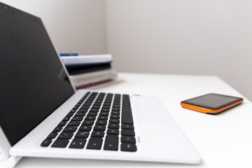 netbook and cell phone on white table, in office