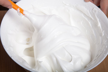 Whipped egg whites for pastry in a white ceramic bowl