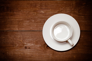 White cup on old wooden table. Toned