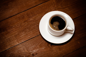 White cup of coffee on old wooden table. Toned