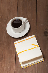 White cup of coffee and notebook on old wooden table