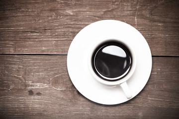 White cup of coffee on old wooden table. Toned