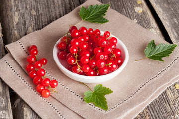 bowl of red currant on wooden background, horizontal close-up