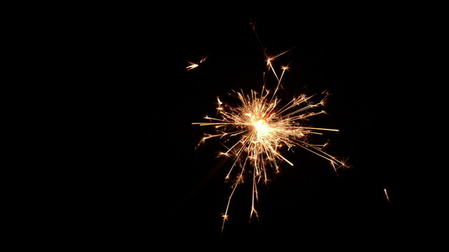 Burning christmas sparkler isolated on a black background. Diagonal single sparkler.
