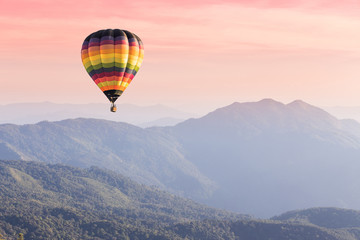 Naklejka premium Hot air balloon above high mountain at sunset