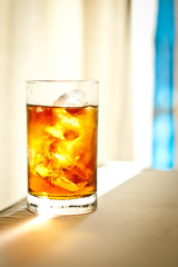 A glass of tea. A glass on the table. Glass covered with drops . Iced tea with lemon juice and ice. Excellent quench your thirst