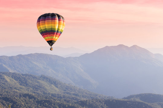 Hot air balloon above high mountain at sunset