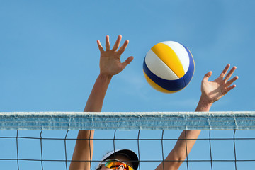 Beach volley ball player jumps on the net and tries to blocks the ball - obrazy, fototapety, plakaty