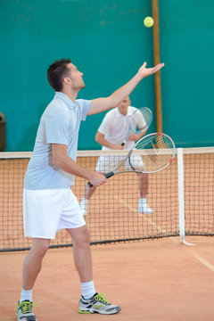 young man doing tennis service