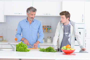 Father and son in kitchen, preparing vegetables