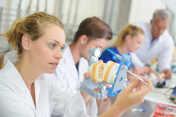 Female technician holding dentures in a clamp