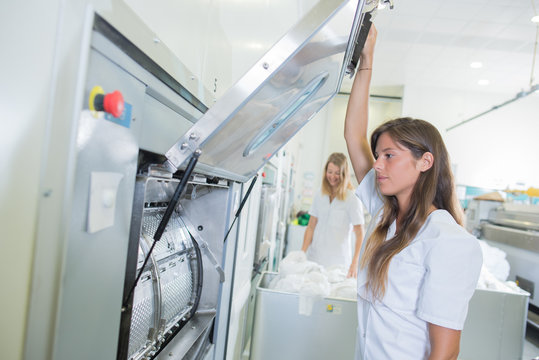 Lady Lifting Open Door Of Machine In Professional Laundry