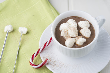 A big cup of hot cocoa with marshmallows decorated with striped
