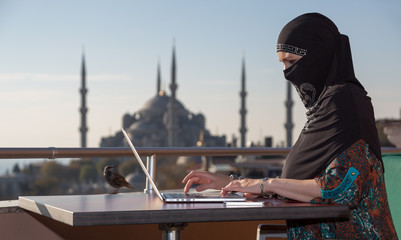 Traditionally dressed Muslim Woman working on computer