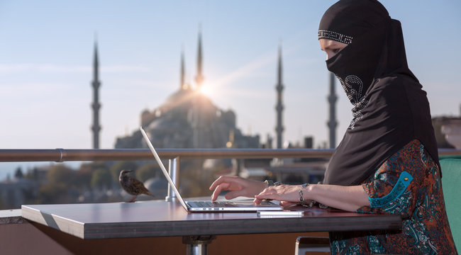 Traditionally dressed Muslim Woman working on computer
