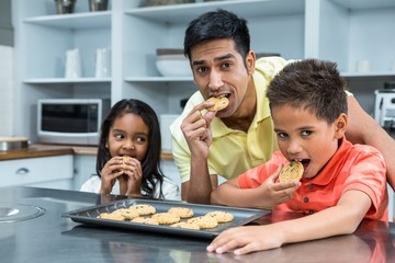 Smiling father with his children eating biscuits