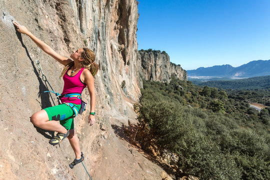 Hippie Style Female Climber ascending Vertical Orange Rock