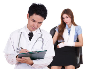 doctor writting medical report with woman injured arm