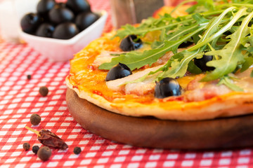 Homemade pizza with bacon, olives and arugula