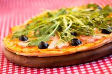 Homemade pizza with bacon, olives and arugula