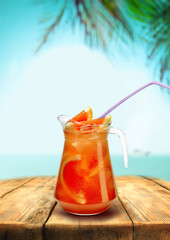 Lemonade beach bar pub, red grapefruit drink with straw wooden table, background of palm trees sea letnegeo
