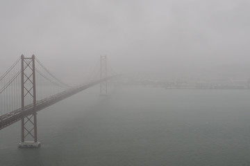 The bridge of the 25th April in the bad weather. The bridge is connecting the city of Lisbon to the municipality of Almada on the left bank of the Tejo river, Lisbon, Portugal.