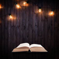 Opened book on a wooden background with Light bulbs