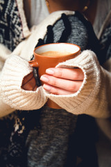 Girl in cardigan holding a cup of coffee. Close-up