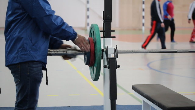 Competitions on powerlifting. Assistant hangs the weight on the barbell