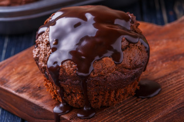 Chocolate muffins with chocolate syrup on dark background.