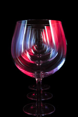 Fototapety  Imprezowe kieliszki do wina w klubie nocnym oświetlone czerwonym, niebieskim, liliowym światłem, życiem nocnym i przemysłem rozrywkowym, obiekty w rzędzie na białym tle na czarnym tle