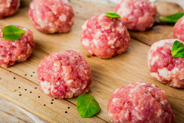 Raw meatballs of beef and pork on a wooden board