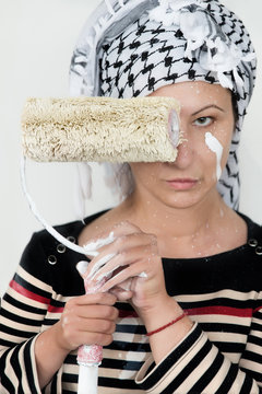 Woman holding paint roller in front of face