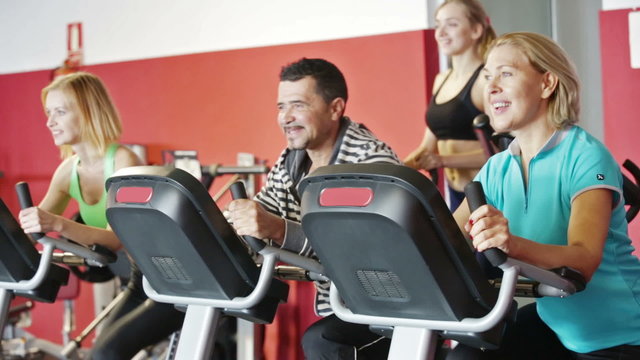 Women and man doing powerlifting on machines in jym