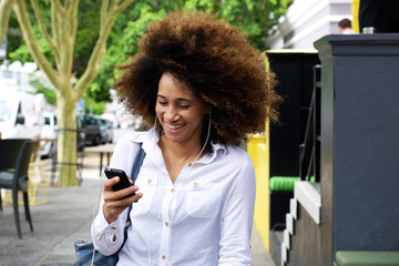 Young black woman smiling with earphones and mobile phone