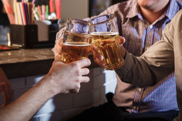 Happy friends drinking beer at counter in pub