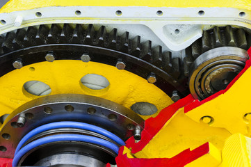 Drive gear and bearings, cross section of bulldozer sprocket internal mechanism, large construction machine with bolts and yellow paint coating, heavy industry, detail 