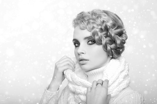 portrait of a beautiful young blonde woman on a light background. hair tied in a braid. girl wearing a warm sweater and scarf. copy space..