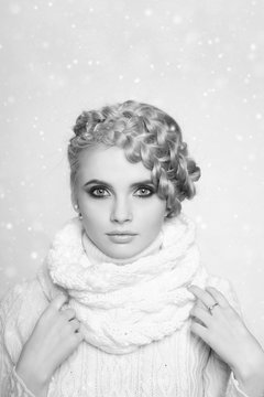 portrait of a beautiful young blonde woman on a light background. hair tied in a braid. girl wearing a warm sweater and scarf. copy space..