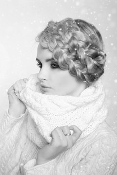 portrait of a beautiful young blonde woman on a light background. hair tied in a braid. girl wearing a warm sweater and scarf. copy space..